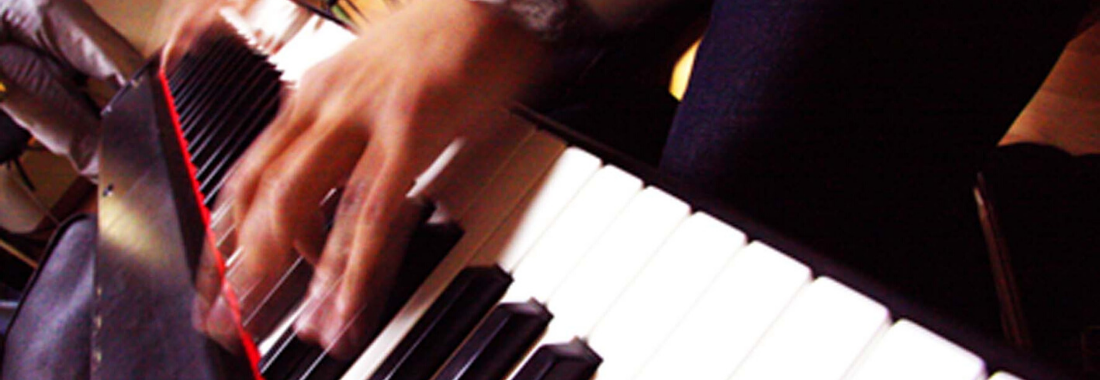 manos tocando un piano en los locales de ensayo