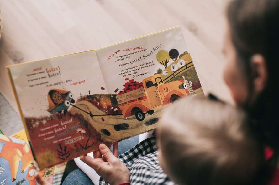 persona leyendo libro a bebe