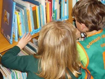 niño y niña buscando libros a escondidas en la biblioteca