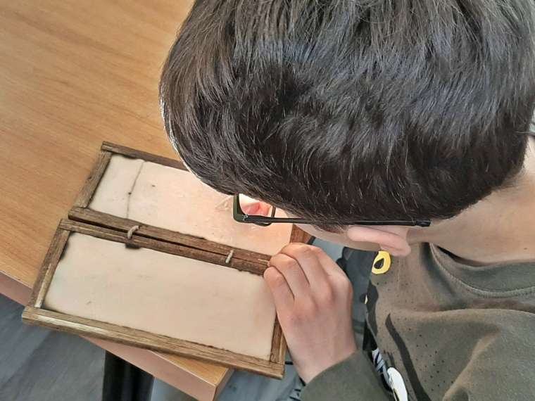 niño con escribiendo en papiros romanos