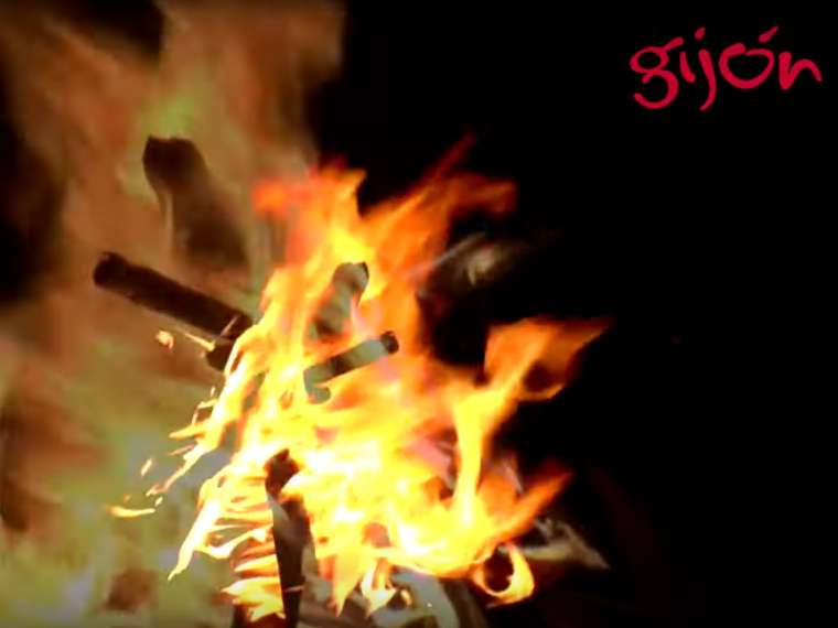 Imagen del vídeo sobre San Xuan con una hoguera y el logo de Gijón