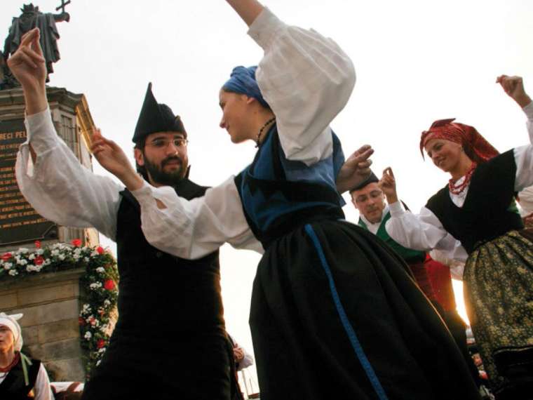 Grupo folklórico asturiano bailando ante la funte de Pelayo enramada