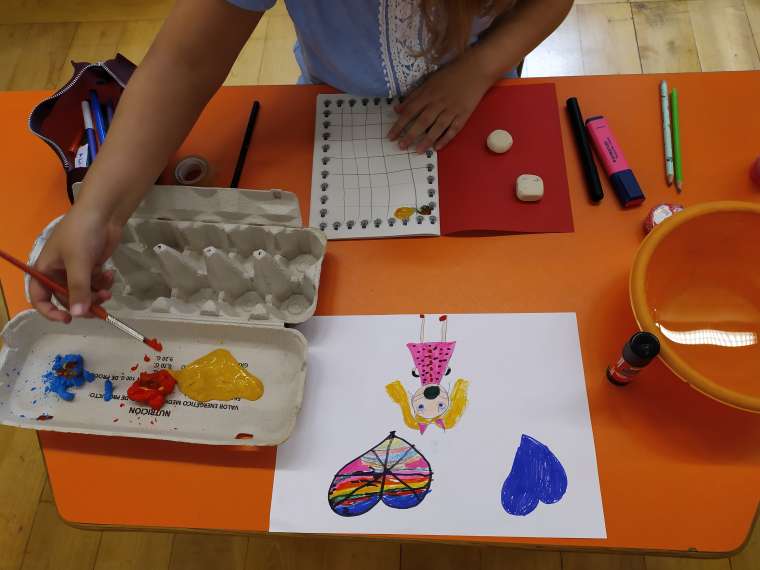 Imagen de una mesa de color naranja con varias actividades de manualidades desarrollándose sobre ella.