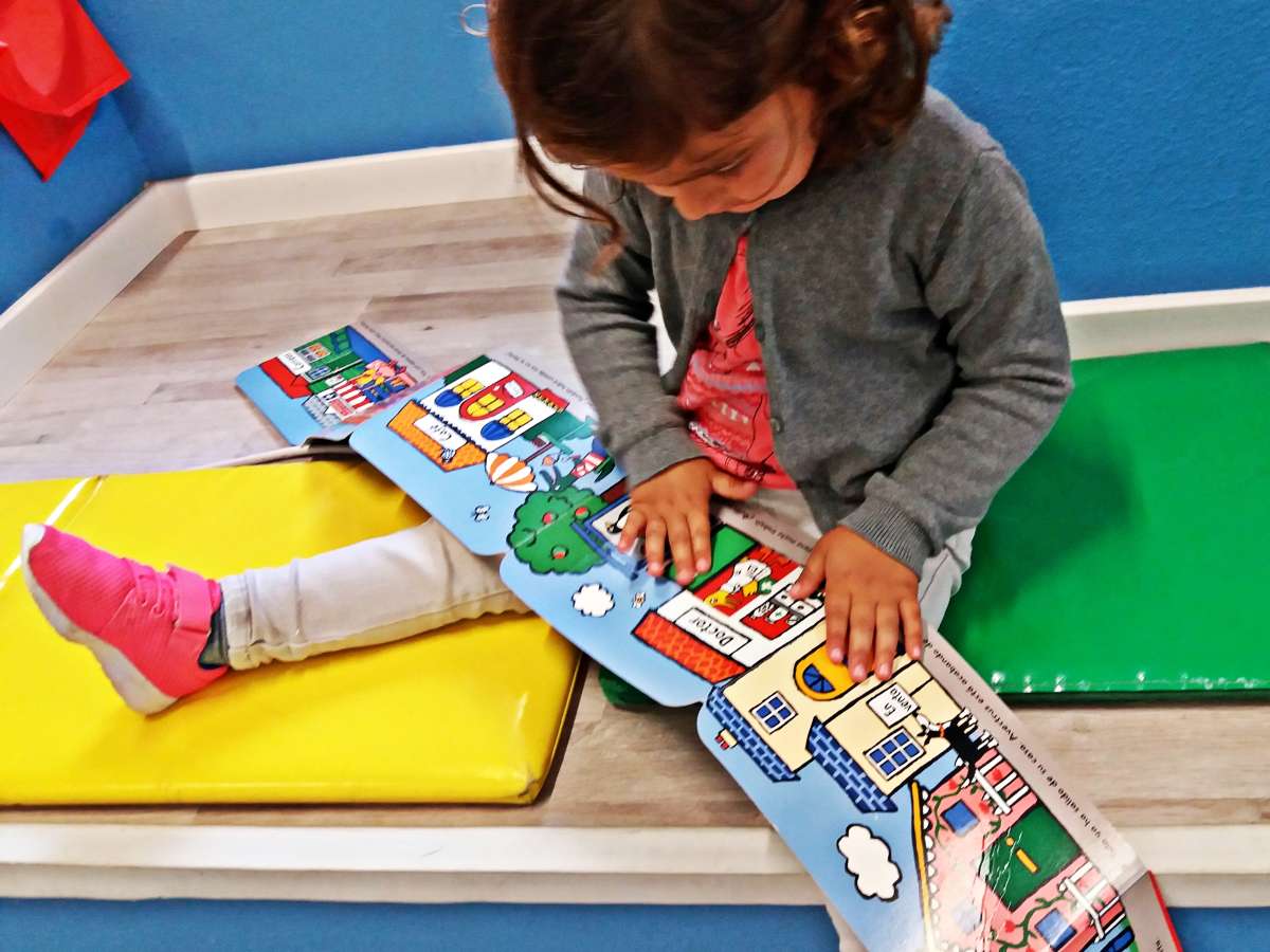 niña leyendo sentada un libro infantil