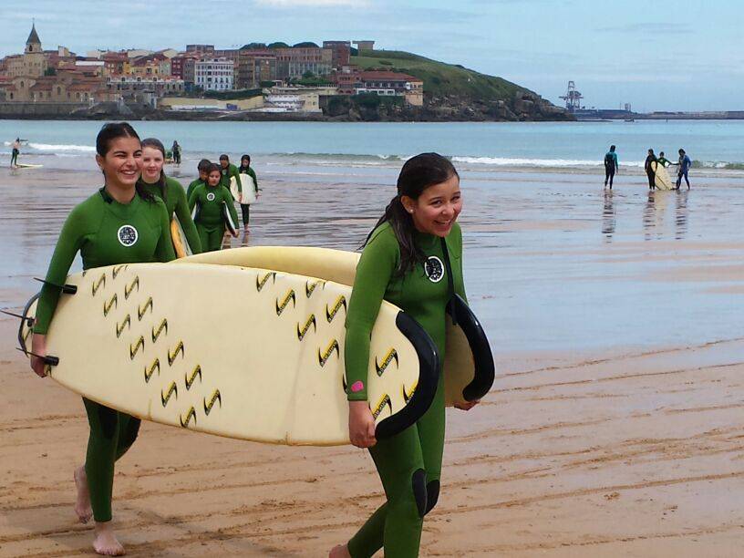 escolares con tabla de surf en la playa