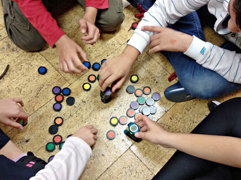 manos de niños jugando con elementos de conocimiento en el suelo