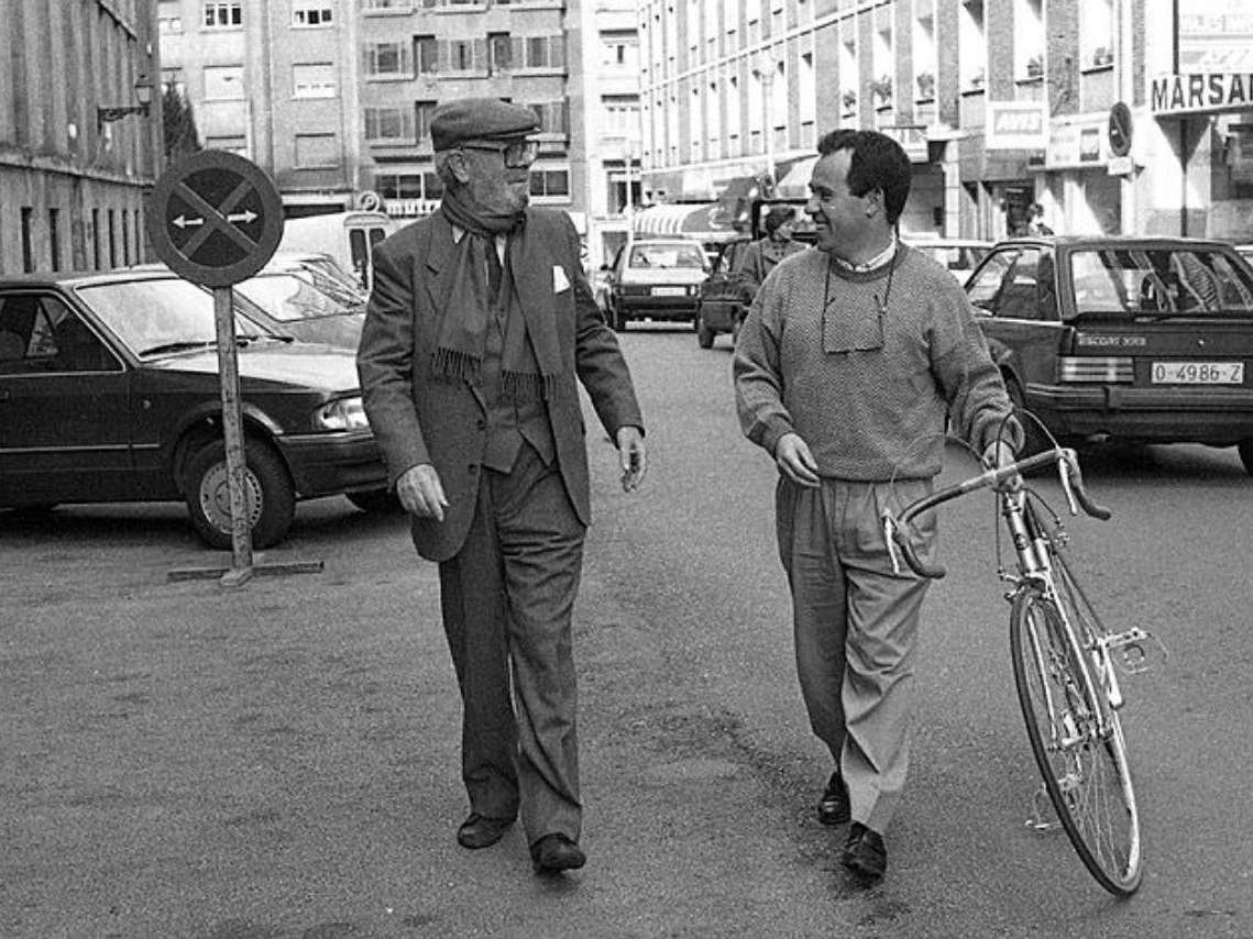 El director de cine Luis García Berlanga con la bicicleta de José Enrique Cima, ciclista y periodista deportivo de "La Nueva España". Autor / Taller: Vélez Abascal, José (1931-2012) Archivado: Muséu del Pueblu d'Asturies